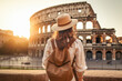 Female traveler with a backpack in front of the Colosseum in Rome, Italy