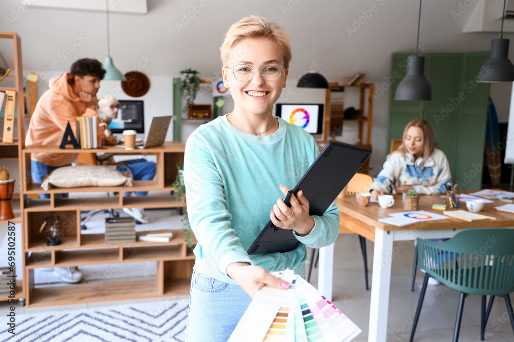 Female graphic designer with tablet and color palettes in office