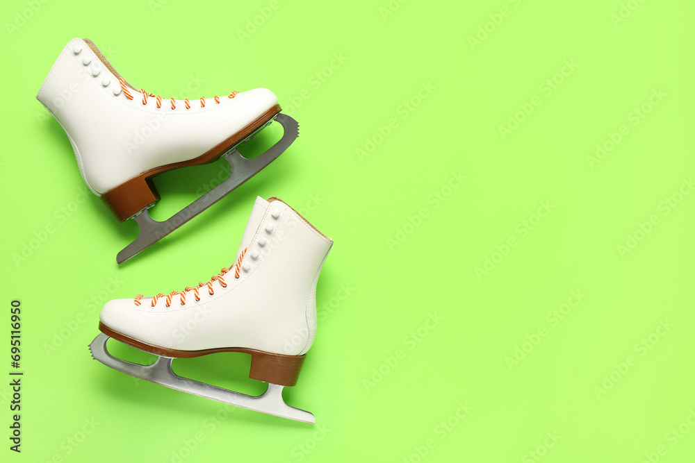 White ice skates on green background