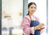 © David - Portrait of happy waitress standing at restaurant entrance. SME entrepreneur young business asian woman attend new customers near door. Smiling small business owner showing open sign in her shop.