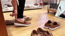 Lady in a shoe shop trying new pairs of comfortable shoes, sneakers