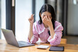 © David - Portrait of tired young business Asian woman work with documents tax laptop computer in office. Sad, unhappy, Worried, Depression, or employee life stress concept