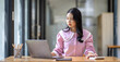 © David - Photo of cheerful joyful young asian business woman in the office working on laptop digital project sitting at desk.