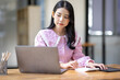 © David - Photo of cheerful joyful young asian business woman in the office working on laptop digital project sitting at desk.