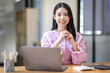 © David - Photo of cheerful joyful young asian business woman in the office working on laptop digital project sitting at desk.