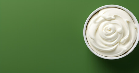 Wall Mural - Top view of bowl with white quark or cream on side of green background with copy space