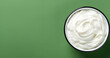 Top view of bowl with white quark or cream on side of green background with copy space
