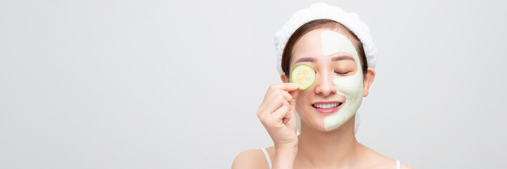 Wall Mural - Beautiful girl holding a slice of cucumber in front of her face.