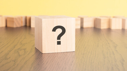 Sticker - question mark written on wooden cube lying on table, business and education concept. close-up cubes