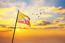 Waving Flag Of Bhutan Against The Background Of A Sunset Or Sunrise. Bhutan Flag For Independence Day. The Symbol Of The State On Wavy Fabric.