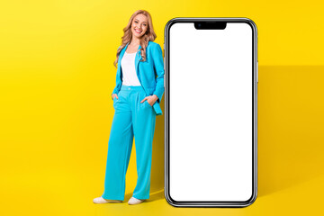 Canvas Print - Full size photo of pretty girl dressed blue jacket trousers stand near smartphone screen empty space isolated on vivid yellow background