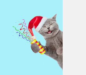 Aufkleber - Happy cat wearing red santa hat holds exploding firecracker and looks from behind empty white banner. Isolated on blue background