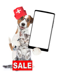 Poster - Smart jack russell terrier dressed like a doctor with stethoscope on his neck hugs tiny kitten and shows big smartphone with white blank screen in it paw. Cat shows ignboard with labeled 