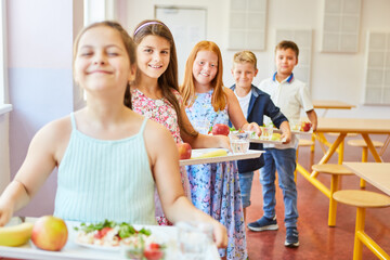 Wall Mural - Smiling students standing in line holding food trays