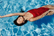 © SHOTPRIME STUDIO - Young woman in the pool in a red swimsuit with a beautiful smile lying on the water and swimming in the sun swimming in the pool, the concept of relaxing on vacation.