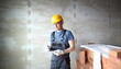 © H_Ko - Portrait of thoughtful male wearing protective outfit and gloves to prevent any harm from construction trauma and injury. Builder holding paper tablet and writing everything down. Building concept