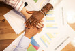 © ADDICTIVE STOCK - Crop diverse coworkers stacking hands on table with statistical charts papers in office