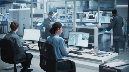 Poster - Caucasian Male Programmer And Hispanic Female Assembly Line Operator Using Desktop Computers At Modern Factory With Robotic Arms. Diverse Colleagues Working On the Production Of High-Tech Devices.