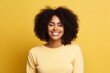 © Markus Schröder - Portrait of a cheerful afro-american woman in her 20s sporting a long-sleeved thermal undershirt against a soft yellow background. AI Generation