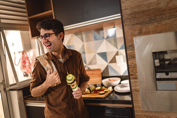 Young man smiling, holding a vegetable skewer.