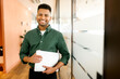 © Vadim Pastuh - Working with joy. Smiling cheerful indian businessman wearing casual green shirt standing with laptop computer in office, looking at camera, proud and ambitious latin start-up owner