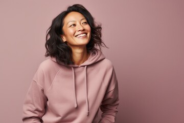 Wall Mural - Portrait of a glad asian woman in her 40s sporting a comfortable hoodie against a pastel or soft colors background. AI Generation