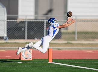 Wall Mural - Athletic young football players making amazing plays running with, catching, kicking and throwing the ball during competitive games