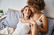 cheerful interracial lesbian couple enjoying morning time together in bedroom, joyful moments