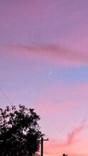 Small Sliver Of A Waxing Crescent Moon Showing During A Colorful Sunset Sky