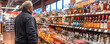 © Degimages - A man standing in front of a display of bottles in alcohol store.