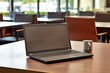 © Izhar - A laptop with its lid open is resting on a table in the office workspace's meeting room.