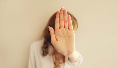 Upset young woman shows stop, no or enough sign with palm of hand, refusal gesture, domestic violence