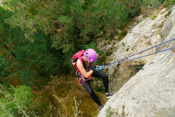 Woman initiating rappel with a forest background