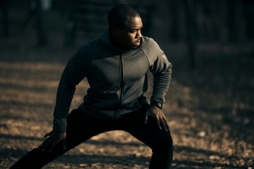 Wall Mural - Male athlete doing stretching exercises in a park