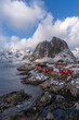 View of fishermen village with typical red houses in Lofoten with snow capped mountains in the background