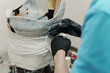 Closeup of crop unrecognizable male worker in black rubber gloves making hip disarticulation prosthesis mold with wet plaster in professional workshop