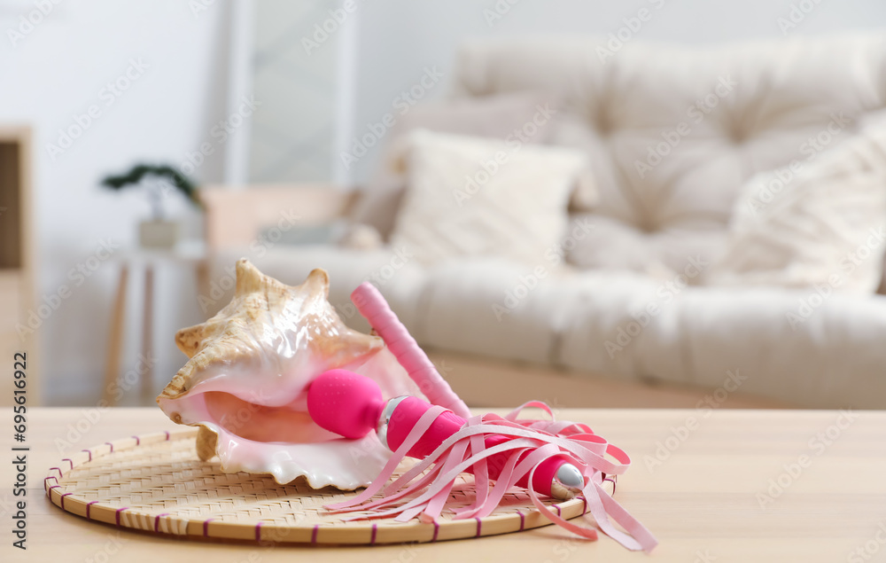 Seashell with vibrator and whip on table in living room, closeup