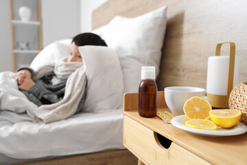 Wall Mural - Lemon with medications and tea cup on table of ill little boy in bedroom, closeup