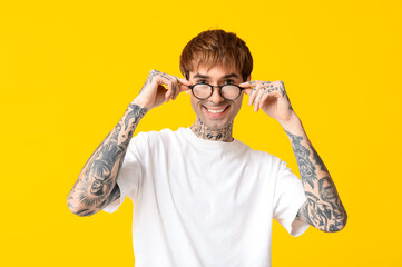 Sticker - Happy handsome young tattooed man with eyeglasses on yellow background