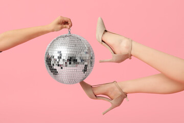 Wall Mural - Female legs in trendy high heels and hand with disco ball on pink background