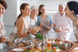 © JackF - Young woman in apron drinking wine and chatting with group during master class