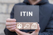Man holding wooden cubes with icons and black sticky note with acronym: ITIN. ITIN - Individual Taxpayer Identification Number Business concept.