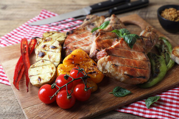 Delicious grilled meat and vegetables served on wooden table, closeup