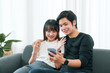 © amnaj - Young Asian couple in love using smartphone together at home.