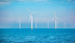 Windmill turbines generating electric green energy with a blue sky green energy concept in the Netherlands, windmill turbines at sea
