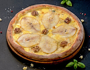 Canvas Print - Pizza with nuts and pear on a black background. Delicious pizza with pears, gorgonzola cheese, walnuts.