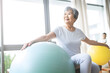 © Zay Win Htai - Senior Asian woman doing exercise with a swiss ball at a gym