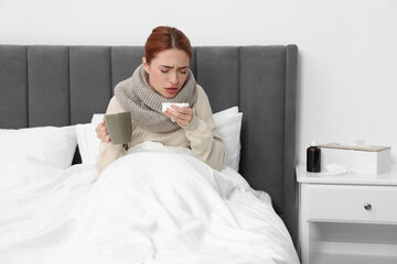 Canvas Print - Woman with cup of drink and tissue coughing at home. Cold symptoms