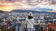 A tourist woman on a sightseeing trip enjoys the beautiful panoramic winter sunrise view of the cityscape of Bergen, Norway, Scandinavia