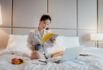 Asian teenage girl resting on the mattress After a full night's sleep And working in the morning in the bedroom. She is cheerful, bright, and happy.